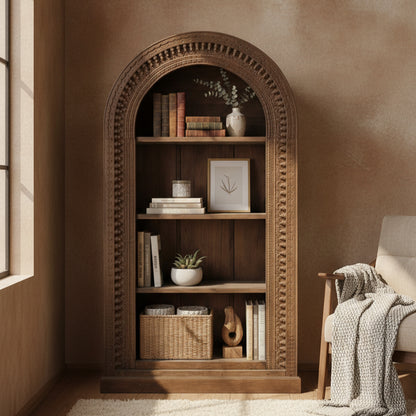 Wooden display shelf with intricate tribal carvings, featuring multiple shelves holding books, decorative vases, framed art, and woven baskets, placed in a cozy living space.
