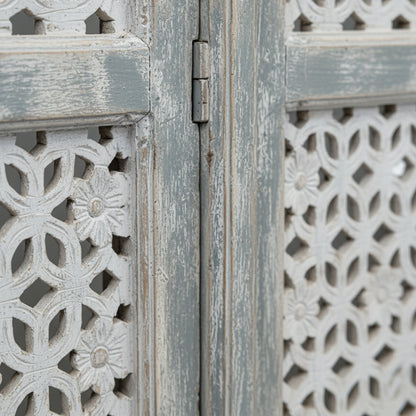 Close-up of a carved wooden room divider with floral pattern and distressed finish