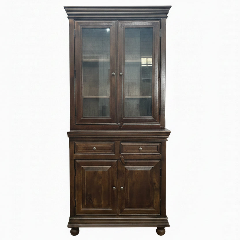 Tall wooden display cabinet with glass-paneled upper doors and solid lower doors, featuring a rich dark finish and traditional handcrafted design for elegant decor.
