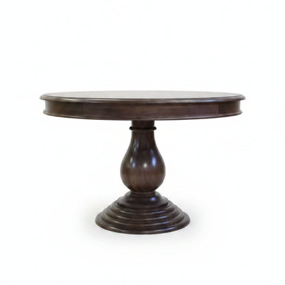Elegant round wooden dining table with a polished dark finish, featuring a sturdy carved pedestal base, reflecting handcrafted tribal decor artistry.