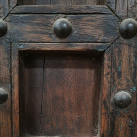 Close-up of rustic wooden tribal handicraft panel with metal studs and weathered texture
