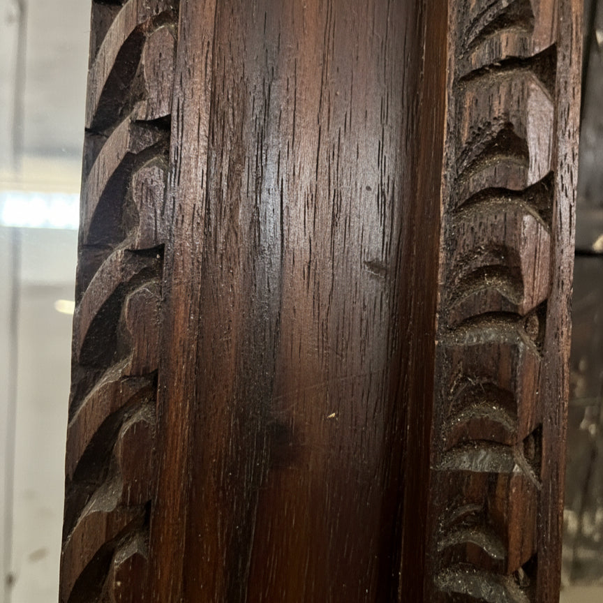 Close-up of hand-carved dark wooden frame with intricate tribal patterns