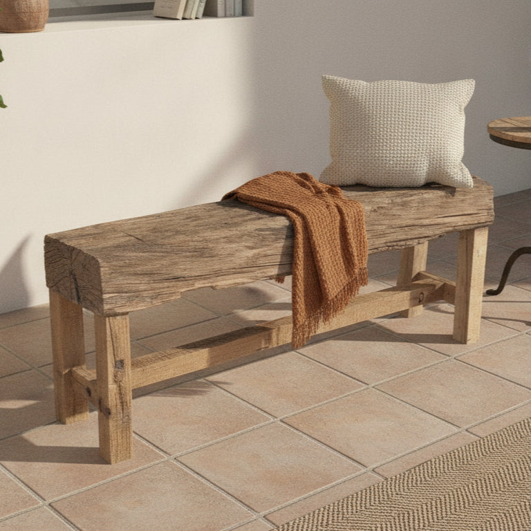 Rustic wooden bench with a natural timber finish, adorned with a textured cushion and a warm brown throw, showcasing handcrafted tribal-inspired decor.