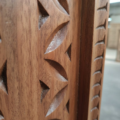 Close-up of hand-carved wooden panel with geometric tribal patterns