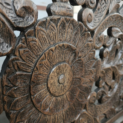 Close-up of hand-carved wooden floral wall art with intricate tribal patterns