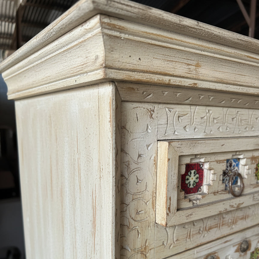 Hand-carved wooden dresser corner with intricate tribal patterns and decorative drawer pulls