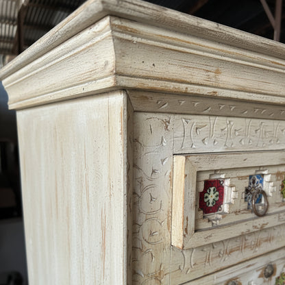 Hand-carved wooden dresser corner with intricate tribal patterns and decorative drawer pulls
