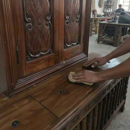 Hand polishing carved wooden tribal handicraft furniture in workshop