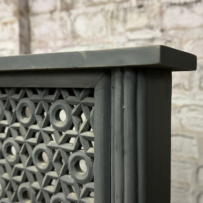 Hand-carved wooden panel with geometric tribal pattern and dark finish, close-up