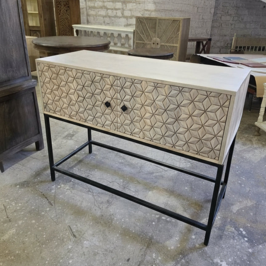 Wooden bar cabinet with intricate tribal-inspired geometric carvings on the front drawer, set on a sturdy black metal frame, ideal for stylish home decor.