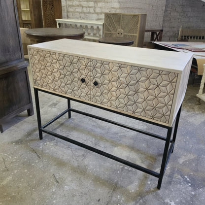 Wooden bar cabinet with intricate tribal-inspired geometric carvings on the front drawer, set on a sturdy black metal frame, ideal for stylish home decor.
