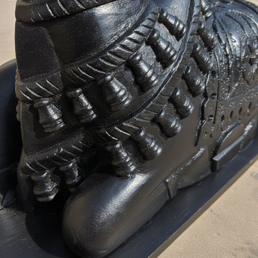 Carved black wooden sculpture with intricate tribal patterns and detailed ornamentation