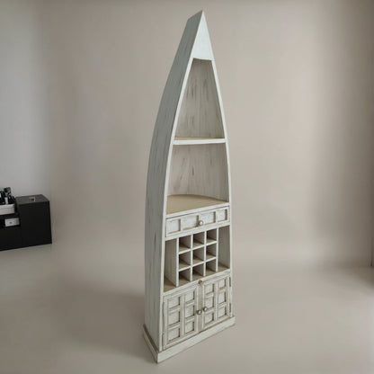 Tall wooden display unit shaped like a boat with open shelves, small drawers, and a wine rack, featuring a rustic white finish suitable for tribal handicraft decor.