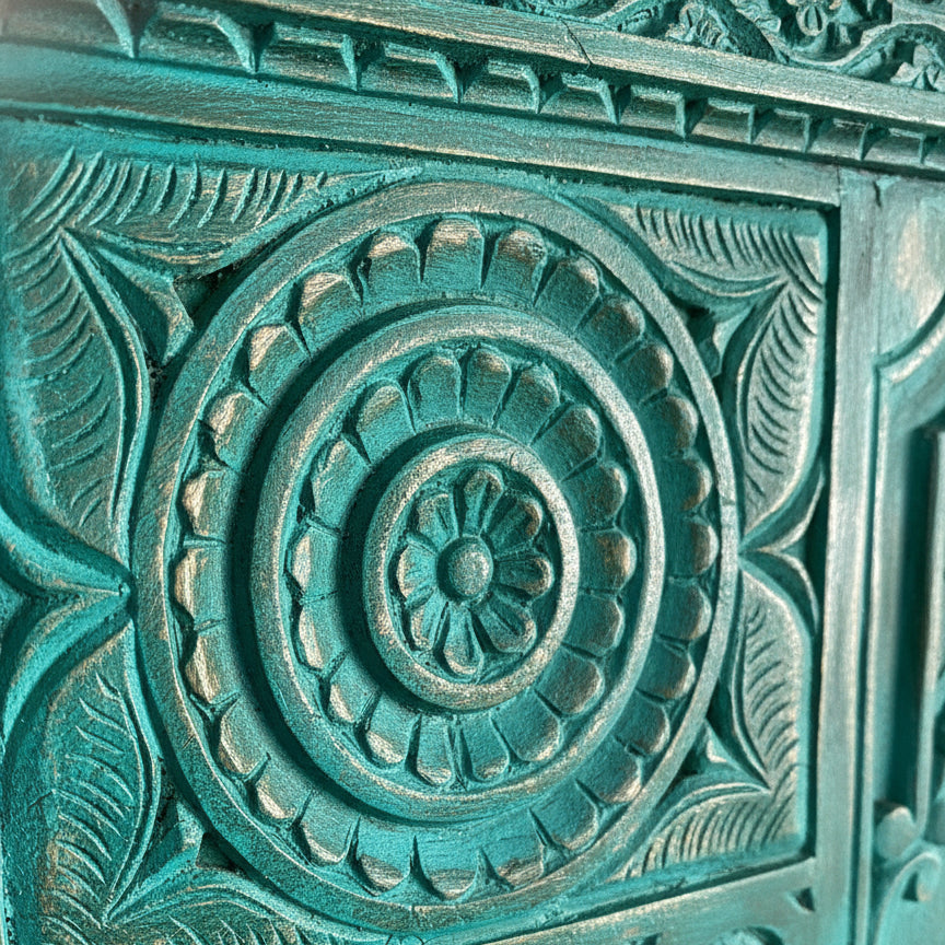 Close-up of intricate teal-painted wooden panel featuring handcrafted tribal floral and leaf motifs with detailed carvings, showcasing authentic wooden decor artistry.