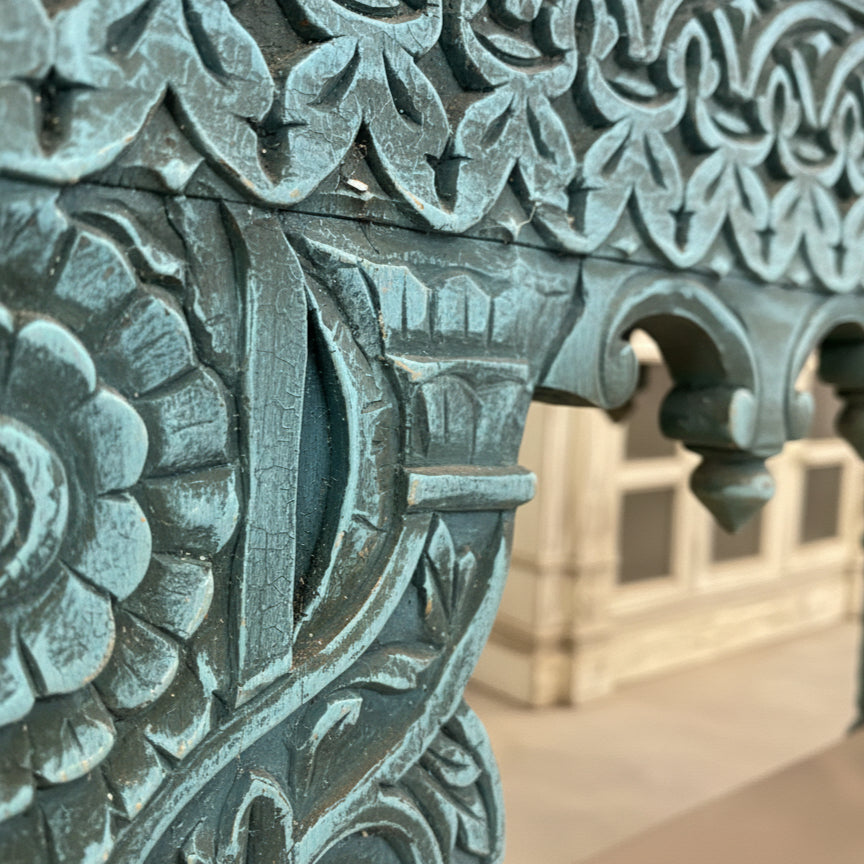 Close-up of blue hand-carved wooden table with floral and geometric patterns