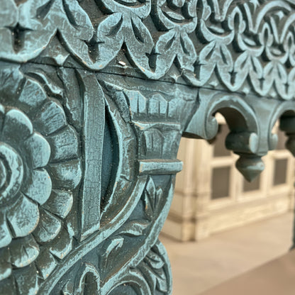 Close-up of blue hand-carved wooden table with floral and geometric patterns