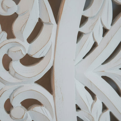 Close-up of white hand-carved wooden panel with intricate tribal floral patterns