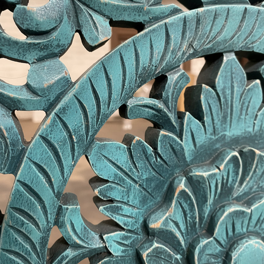 Teal blue hand-carved wooden tribal floral design, close-up, detailed craftsmanship